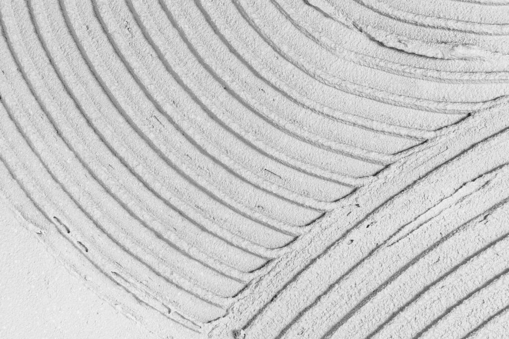 Поверхня стіни, покрита цементно-піщаним розчином із хвилястим візерунком.
