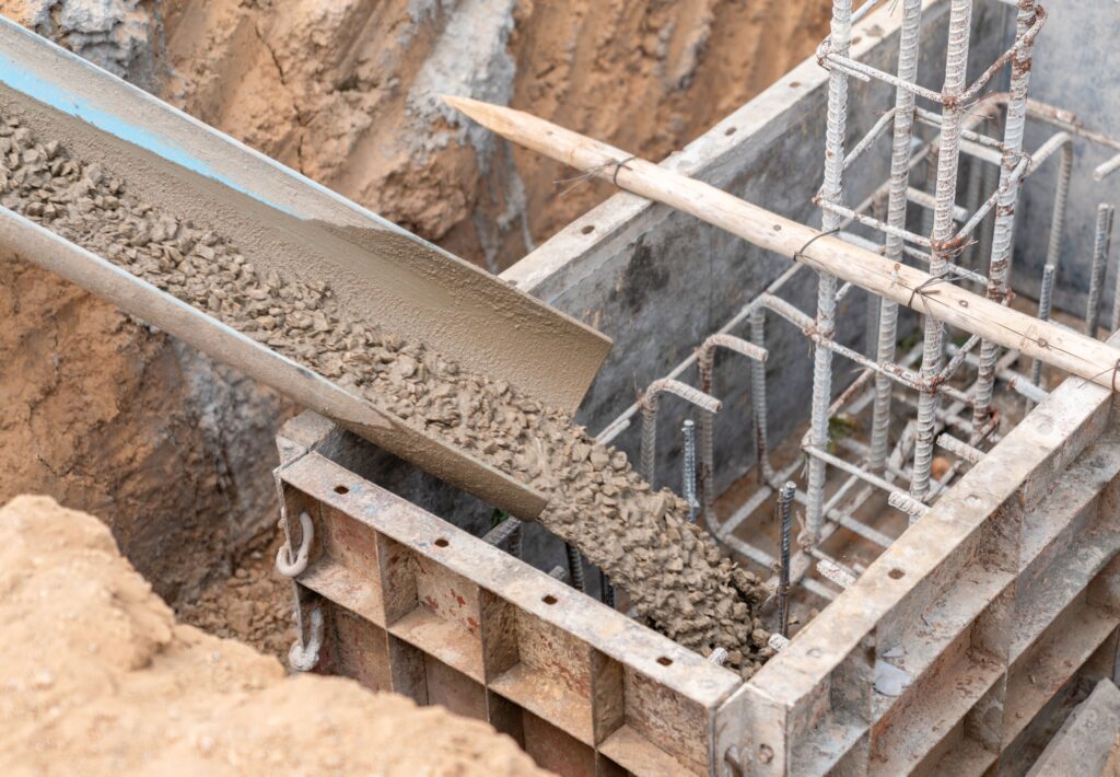 Заливка бетону в основу фундаменту будинку з арматурою.